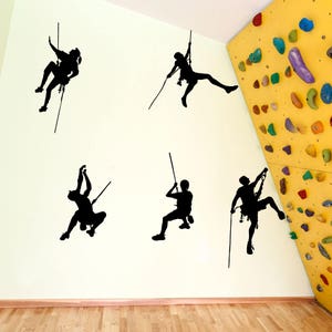 May include: Five black silhouette wall decals of people rock climbing on ropes. The decals are on a white wall with a yellow climbing wall in the background.