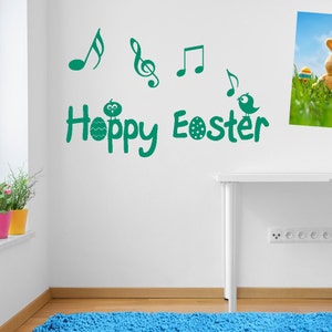 Può includere: Adesivo murale in vinile verde con il testo "Hoppy Easter" e note musicali. Un uccello e un uovo con un viso sono inclusi anche nel design.