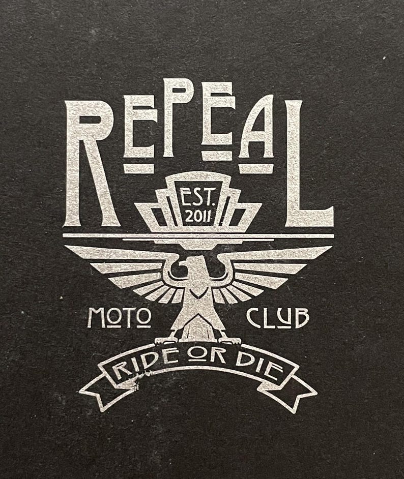 Repeal Moto Club Gremlin Bell Keychain in black leather and steel, featuring a winged wheel motif. A
perfect gift for motorcycle lovers and enthusiasts