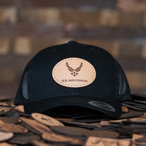 May include: Black trucker hat with a brown leather patch featuring the U.S. Air Force logo and the text "U.S. AIR FORCE."
