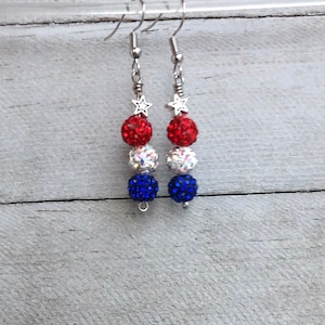 May include: A pair of dangle earrings with red, white, and blue crystal beads and silver star charms.