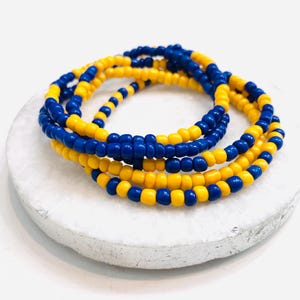 May include: A close-up of a beaded bracelet made with yellow and blue beads. The bracelet is wrapped around itself several times, creating a layered effect.