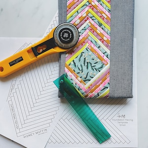 May include: A quilting template for a foundation piecing project. The template is labeled "Foundation Piecing Template Small" and is printed on white paper. A ruler, rotary cutter, and fabric scraps are also visible in the image.