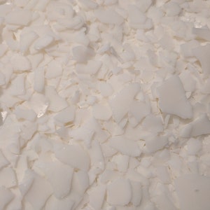 May include: Close-up of white, irregularly shaped flakes. The flakes are scattered across the frame, creating a textured surface. The color is a bright, clean white, suggesting a clean, pure material. The image is well-lit, highlighting the shapes and textures.