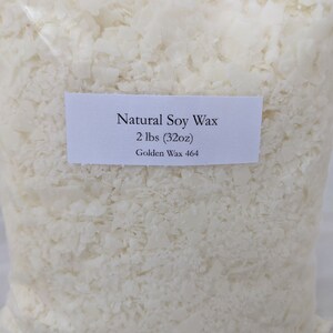 Pu&ograve; includere: Un sacchetto trasparente pieno di cera di soia a scaglie bianco sporco. Un'etichetta bianca sul sacchetto recita "Natural Soy Wax" e "2 lbs (32oz)" con "Golden Wax 464" sotto. La cera ha forme irregolari.