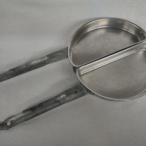 May include: A silver folding camping frying pan with two sections. The pan has a long handle that folds in half.