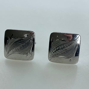 May include: A pair of silver cufflinks with a leaf design.