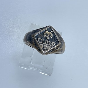 May include: A silver ring with a black enamel diamond-shaped inlay featuring a gold wolf head and the text "CUBS BSA".