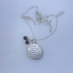 May include: Silver-toned necklace with a pendant that reads "Sister to Sister we'll always be a couple of NUTS off the family TREE." The necklace features a delicate chain and a charm with two dark brown beads.