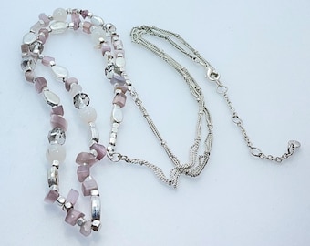 May include: A silver chain necklace with a layered design and a pendant made of pink and white beads.