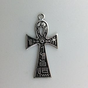 May include: Silver Ankh pendant with intricate details and hieroglyphics. The pendant is in the shape of a cross with a loop at the top.