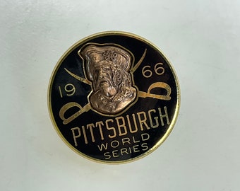 Peut inclure: Épinglette ronde noire et dorée de la Série mondiale de Pittsburgh. Elle présente un pirate de couleur bronze, des épées croisées, l'année 1966 et l'inscription "Pittsburgh World Series".