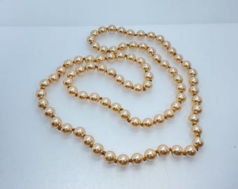 May include: A long strand of cream-colored faux pearl beads. The beads are strung on a thin, brown thread.