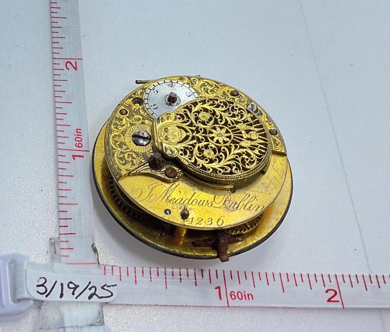 May include: A gold pocket watch with intricate floral engravings and the inscription "J Meadows Dublin 4236".