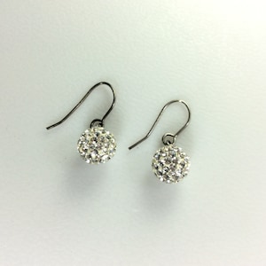 May include: A pair of silver dangle earrings with small round crystal accents.