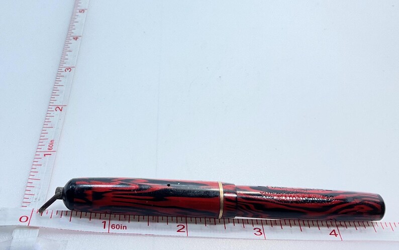 May include: A red and black striped fountain pen with a gold band, measuring approximately 4 inches in length.