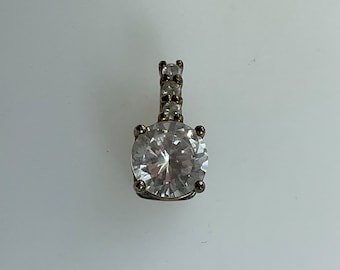 May include: A silver pendant with a large clear round gemstone and a row of smaller clear gemstones on the bail.