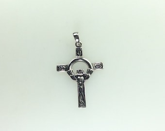 Puede incluir: Un colgante de plata en forma de cruz celta con un diseño detallado. La cruz presenta un anillo con un diseño de nudo celta y un corazón en el centro.