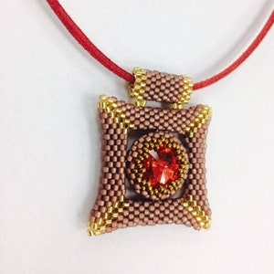 May include: A square-shaped pendant necklace with a red gemstone in the center. The pendant is made of brown and gold beads and is attached to a red cord.