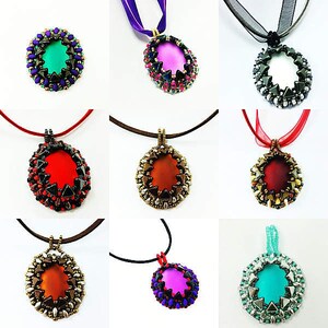 May include: Nine beaded necklaces with different colored oval pendants. Each pendant is surrounded by a beaded halo. The necklaces are on a white background.