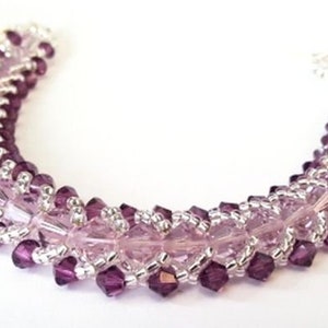 May include: A purple and silver beaded bracelet with a delicate, intricate design. The bracelet is made with small, faceted beads that create a shimmering effect.