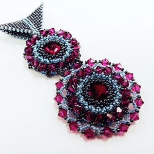 May include: A beaded pendant necklace with two large, circular, flower-shaped charms. The charms are made of dark purple and light blue beads. The pendant is attached to a silver chain.