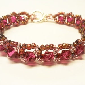 May include: A pink and brown beaded bracelet with a silver clasp. The bracelet is made with small, faceted beads and has a delicate, feminine look.