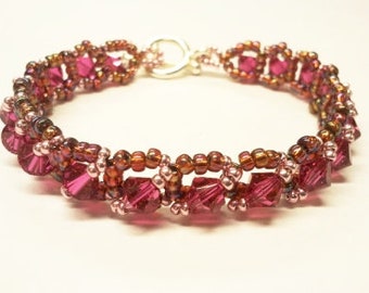 May include: A pink and brown beaded bracelet with a silver clasp. The bracelet is made with small, faceted beads and has a delicate, feminine look.