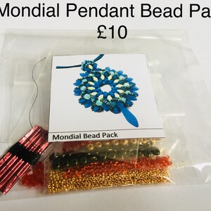 May include: A bead pack for making a blue and white beaded pendant. The pack includes beads in gold, red, and green colours. The pack also includes a length of red thread and a card with a picture of the finished pendant. The card reads "Mondial Bead Pack".