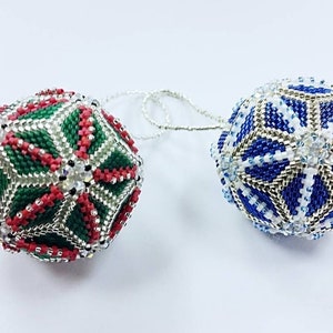 May include: Two beaded Christmas ornaments, one with a green, red, and silver geometric pattern and the other with a blue, white, and silver geometric pattern.