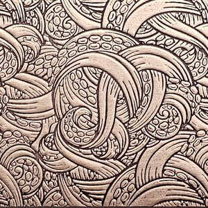 May include: A detailed, close-up view of a textured surface with a repeating pattern. The pattern features swirling, organic shapes with a raised, three-dimensional effect. The color is a muted, metallic bronze, creating a sense of depth and visual interest.