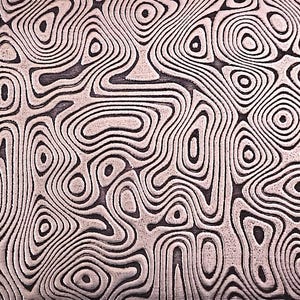 May include: Close-up of a metal surface with a unique pattern. The design features swirling, organic shapes in shades of gray and black, creating a textured, layered effect. The pattern resembles wood grain or a topographical map.
