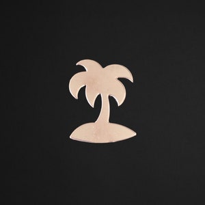 May include: A cutout of a palm tree on an island, made of a metallic material with a rose gold finish.