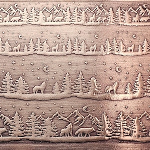 May include: A detailed, copper-colored relief carving depicting a winter forest scene. The design features rows of trees, mountains, wolves, and deer under a starry sky with crescent moons. The artwork has a rustic, textured appearance.