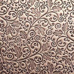 May include: A detailed, close-up view of a textured surface with an embossed floral pattern. The design features swirling vines, leaves, and intricate scrollwork in varying shades of brown and bronze, creating a rich, dimensional effect.