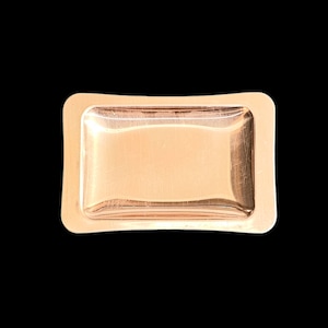 May include: A small, rectangular, copper-colored tray with slightly rounded edges. The tray has a smooth, polished surface.