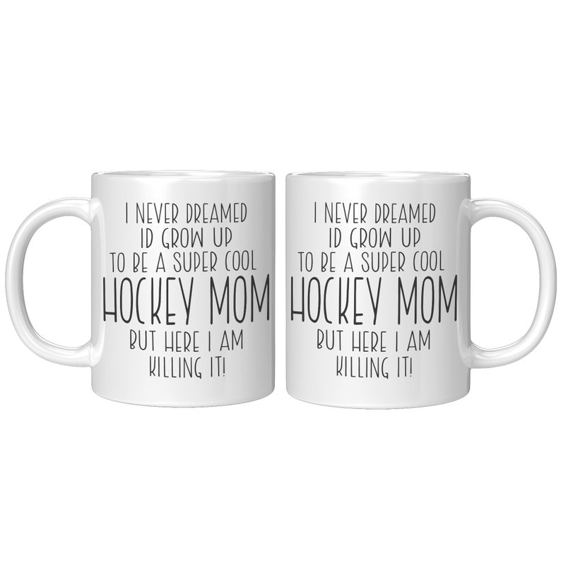 May include: Two white coffee mugs with black text that reads "I never dreamed I'd grow up to be a super cool hockey mom but here I am killing it!"