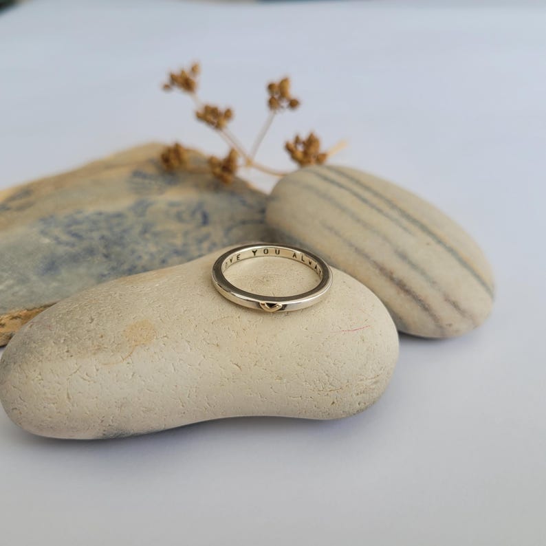 May include: A silver ring inscribed with the words "Love you always" and a small gold heart charm.