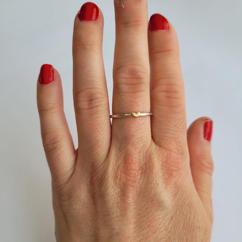 May include: A silver ring with a small gold heart on the band.