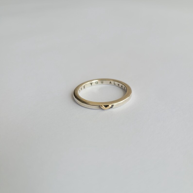 May include: A silver band ring with the words "Love You Always" engraved on the outside and a small gold heart on the inside.