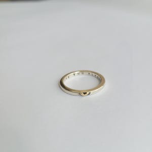 May include: A silver band ring with a gold heart detail. The inscription "Love You Always" is engraved on the inside of the band.