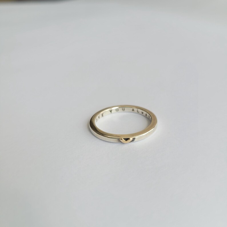 May include: A silver band ring with a gold heart detail. The inscription "Love You Always" is engraved on the inside of the band.