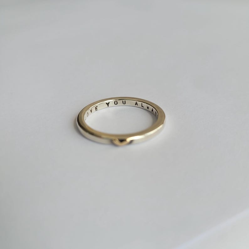 May include: A thin gold band ring with the words "Love You Always" inscribed on the inside of the band. The ring has a small heart-shaped accent on the outside.