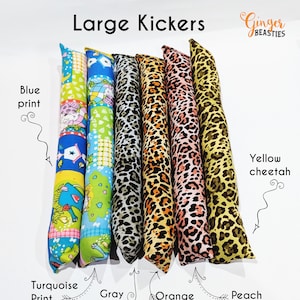 May include: Six catnip kickers in various colors and patterns.  The kickers are made of fabric and are filled with catnip.  The patterns include a blue print, gray cheetah, orange cheetah, peach cheetah, and yellow cheetah.  The kickers are labeled "Large Kickers" and "Ginger Beasties".