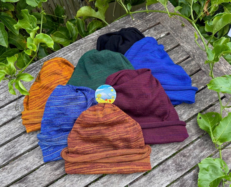 Pu&ograve; includere: Una collezione di sette berretti in vari colori, tra cui arancione, verde, blu, nero e bordeaux. I berretti sono realizzati in un tessuto strutturato e sono disposti su una superficie di legno.