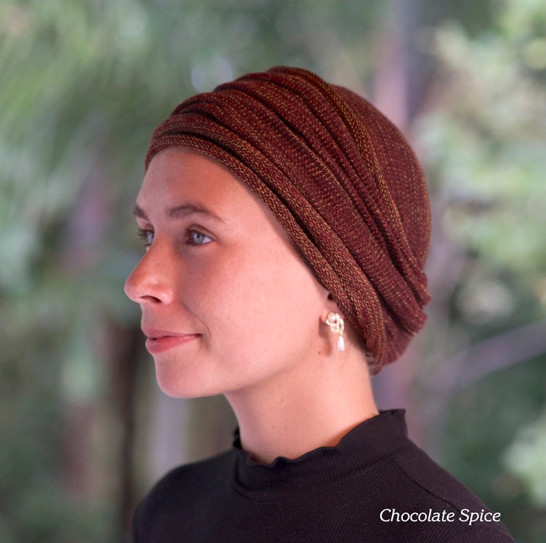Puede incluir: Una mujer lleva una cubierta de cabeza estilo turbante de color marr&oacute;n y dorado con una camisa negra de cuello alto. La cubierta de cabeza se llama "Chocolate Spice".