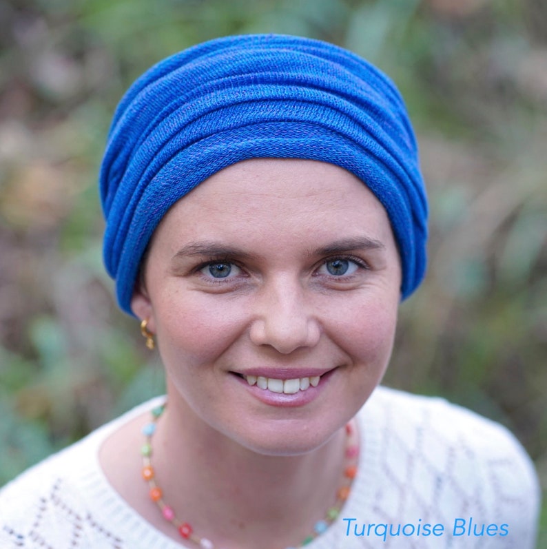 Op de afbeelding: Een vrouw draagt een blauwe tulband met een veelkleurige kralenketting. De tekst "Turquoise Blues" is zichtbaar in de rechterbenedenhoek van de afbeelding.
