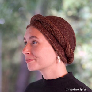 Puede incluir: Una mujer con un turbante de color marr&oacute;n y dorado con un pendiente de perla. El texto "Chocolate Spice" es visible en la parte inferior de la imagen.