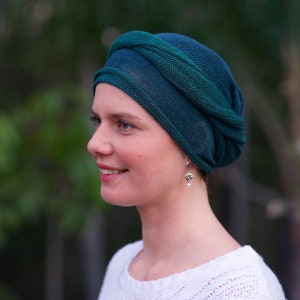 Puede incluir: Una mujer con un turbante de color azul verdoso y verde con un peque&ntilde;o pendiente de perla.