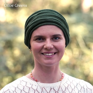 Puede incluir: Una mujer con un turbante de color verde oscuro. Est&aacute; sonriendo y lleva un su&eacute;ter de punto blanco.